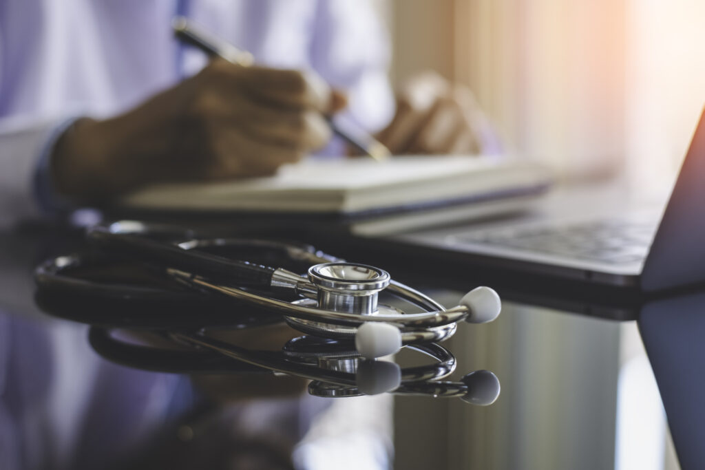 a doctor at a desk and the stethoscope laying on the desk